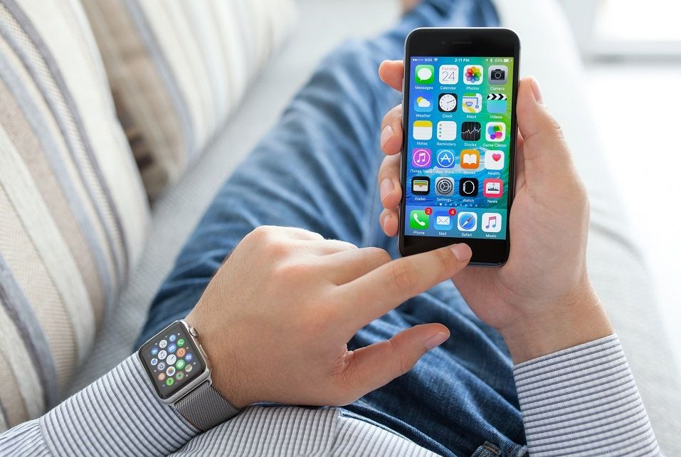 Mannhand mit Apple Watch, die iPhone hält