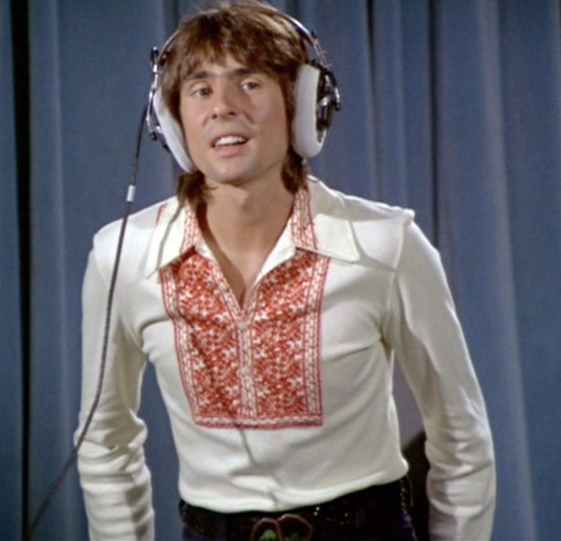   Os Monkees' Davy Jones in front of a blue curtain