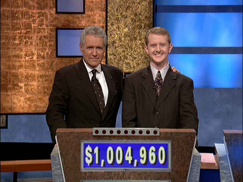 'Jeopardy!' Alex Trebek and casting contestant Ken Jennings. Trebek has his arm around Jennings, who are both wearing suits behind the game podium that reads ,004,960 on the front.